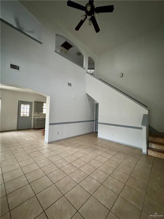 unfurnished living room with light tile patterned floors, ceiling fan, and a high ceiling