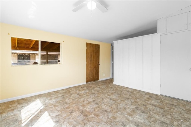 unfurnished bedroom with a ceiling fan and baseboards