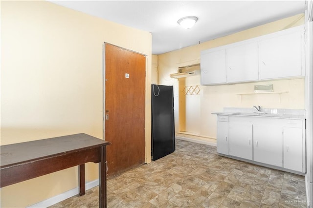 kitchen with a sink, baseboards, white cabinets, and light countertops