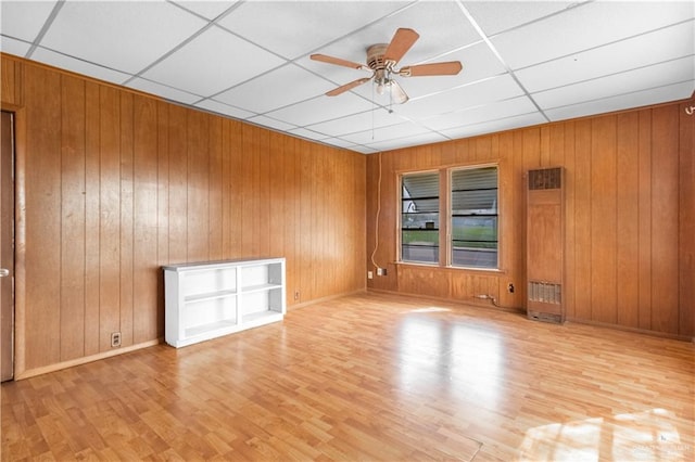 unfurnished room featuring a ceiling fan, wooden walls, wood finished floors, and a paneled ceiling