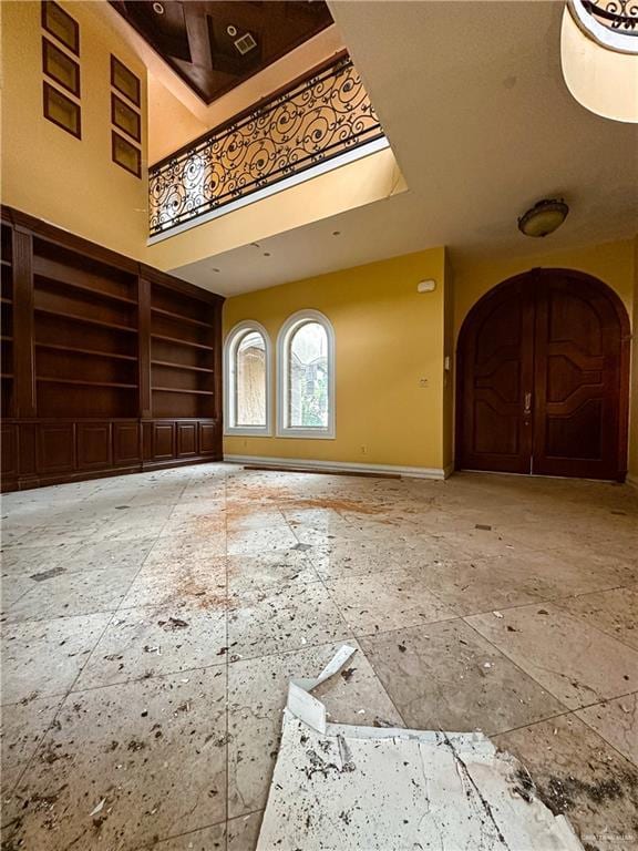 4132 Cosentino Dr, Mcallen, TX 78504 - unfurnished living room featuring arched walkways, a high ceiling, baseboards, and built in shelves
