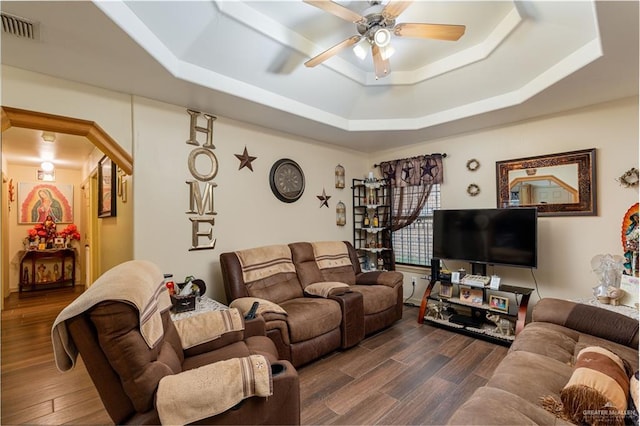 living room featuring ceiling fan, dark hardwood / wood-style floors, and a raised ceiling