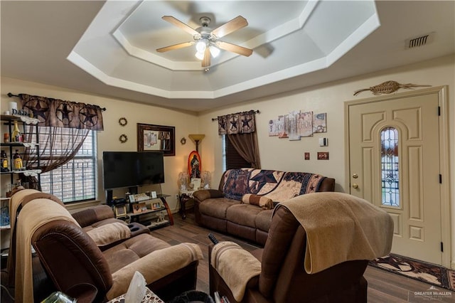 living room featuring ceiling fan, wood-type flooring, and a raised ceiling