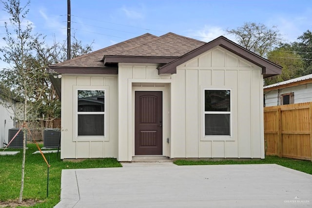 view of front of property with central AC, a front lawn, an outdoor structure, and a patio area