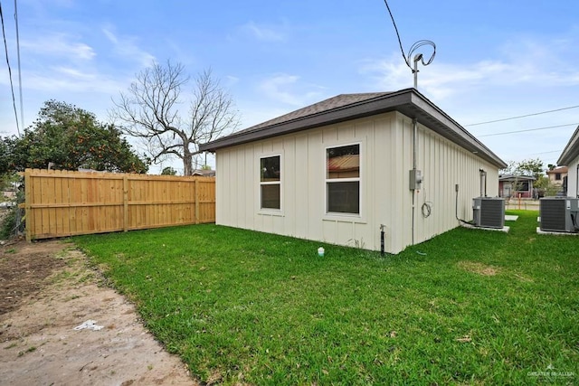 back of house with central AC unit and a yard