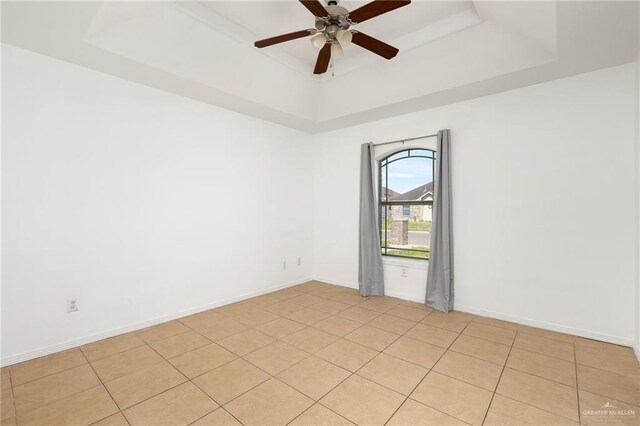 tiled empty room with a tray ceiling and ceiling fan