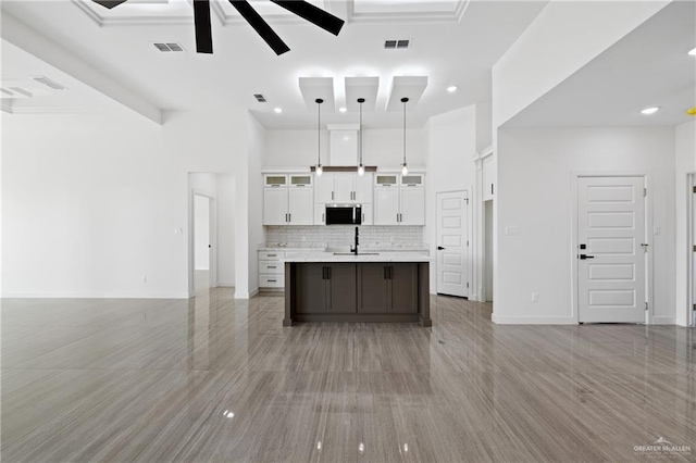 kitchen with visible vents, stainless steel microwave, open floor plan, and a ceiling fan