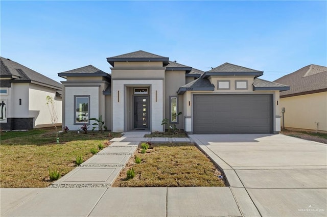 prairie-style home with driveway, stucco siding, an attached garage, and a front yard