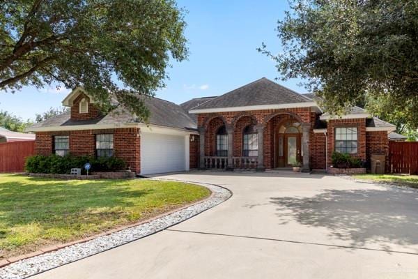 1501 Lookout St, Edinburg, TX 78541 - view of front facade featuring driveway, a garage, covered porch, and brick siding