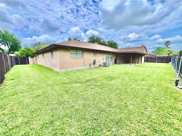 back of property with brick siding, a fenced backyard, a yard, and cooling unit