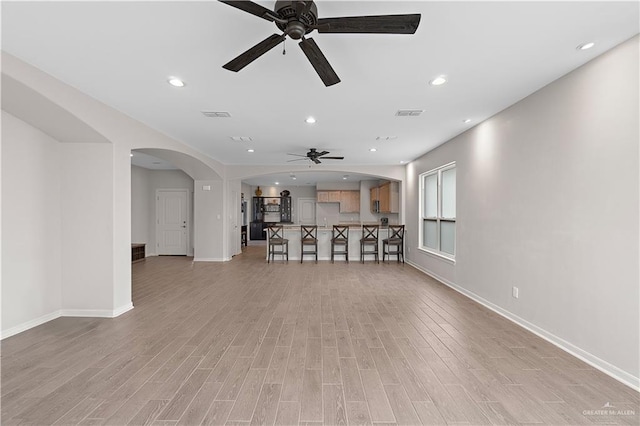 unfurnished living room with light wood-type flooring and ceiling fan