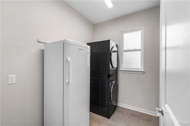 washroom with stacked washer and dryer and light hardwood / wood-style floors