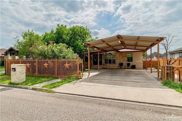 exterior space featuring a carport, fence, stone siding, and driveway