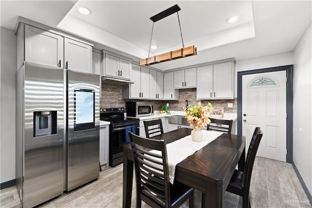 16311 Citrus Dr, Mcallen, TX 78541 - kitchen featuring appliances with stainless steel finishes, light wood-style floors, a tray ceiling, decorative backsplash, and recessed lighting