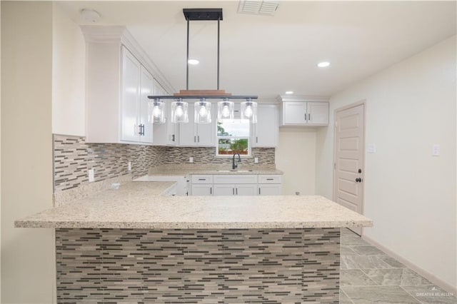 kitchen featuring pendant lighting, kitchen peninsula, sink, and white cabinets