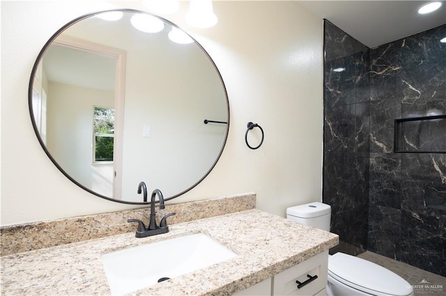 bathroom featuring vanity, toilet, and a tile shower