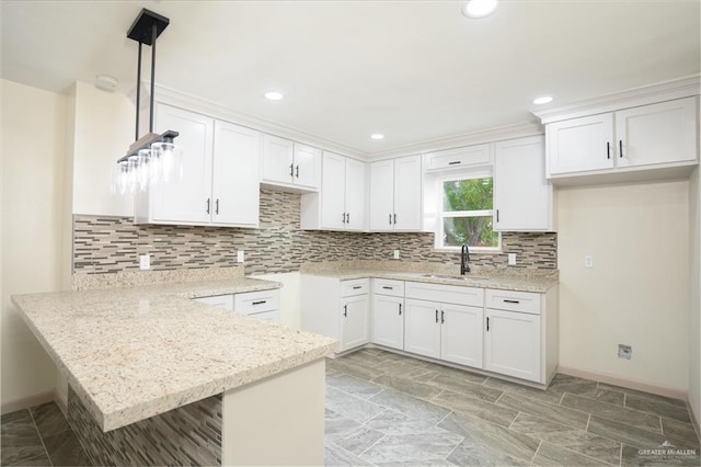 kitchen featuring sink, backsplash, white cabinets, decorative light fixtures, and kitchen peninsula