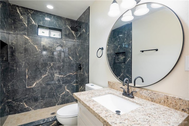 bathroom with vanity, a tile shower, and toilet