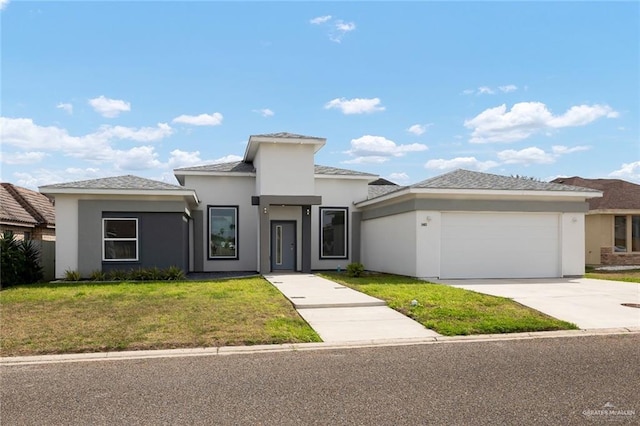 prairie-style house featuring an attached garage, driveway, a front yard, and stucco siding