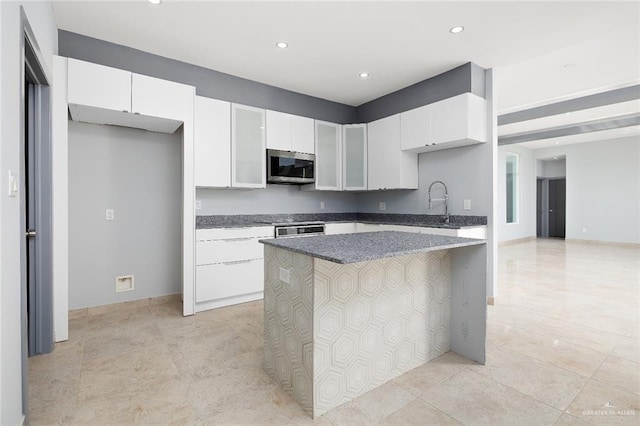 kitchen featuring a kitchen island, stainless steel microwave, white cabinets, and recessed lighting