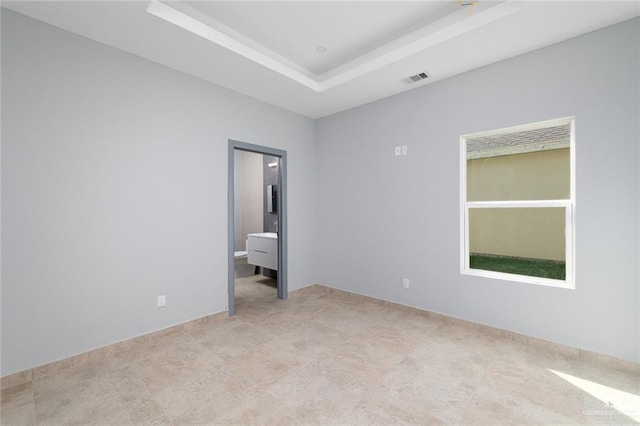 unfurnished bedroom featuring visible vents, a raised ceiling, and ensuite bathroom