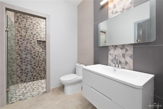 bathroom featuring a stall shower, toilet, tile patterned floors, vanity, and tile walls