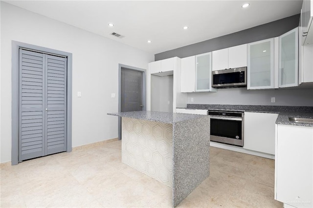 kitchen featuring recessed lighting, stainless steel appliances, visible vents, white cabinetry, and a center island