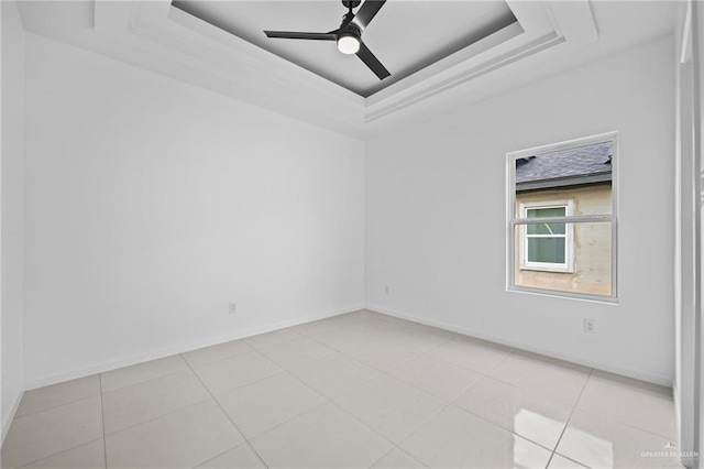 unfurnished room featuring a tray ceiling, baseboards, and ceiling fan