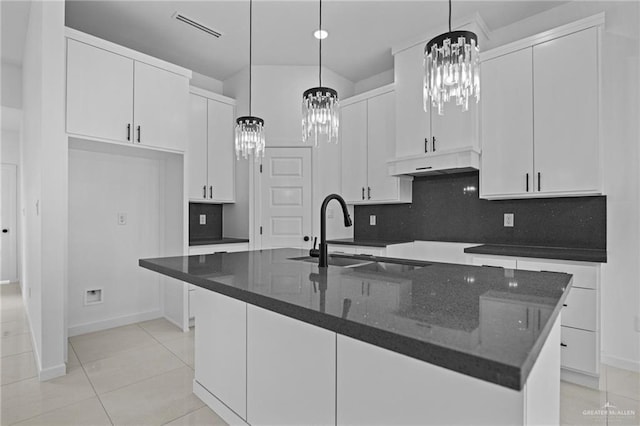 kitchen with visible vents, ventilation hood, a center island with sink, white cabinets, and a sink