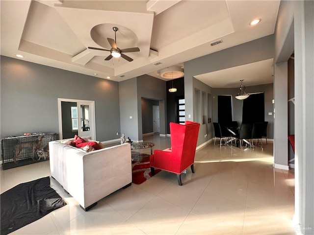 tiled living room featuring a raised ceiling and ceiling fan