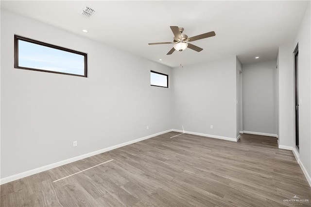 spare room featuring wood finished floors, visible vents, and baseboards