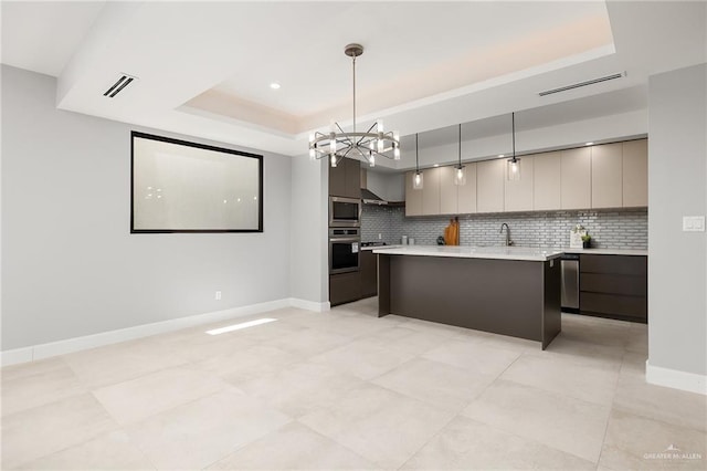 kitchen featuring a raised ceiling, a kitchen island, modern cabinets, appliances with stainless steel finishes, and light countertops