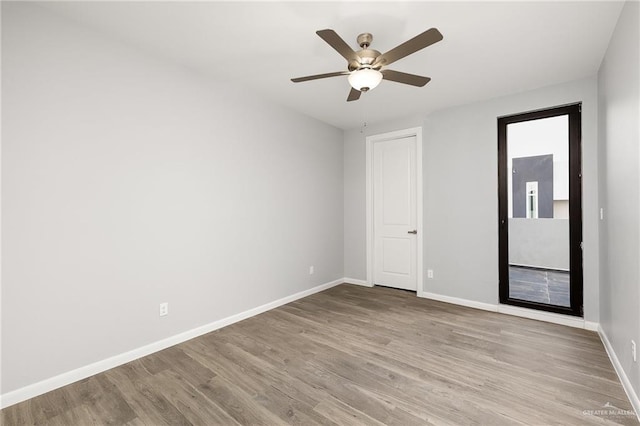 unfurnished room with ceiling fan, wood finished floors, and baseboards