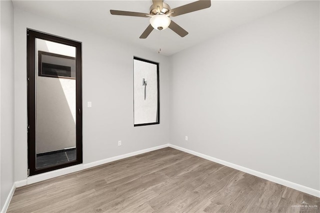 empty room featuring ceiling fan, baseboards, and wood finished floors