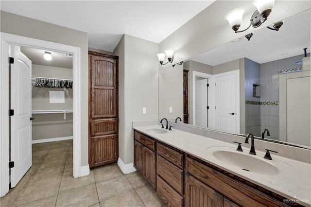 bathroom with tiled shower, tile patterned flooring, vanity, and an inviting chandelier