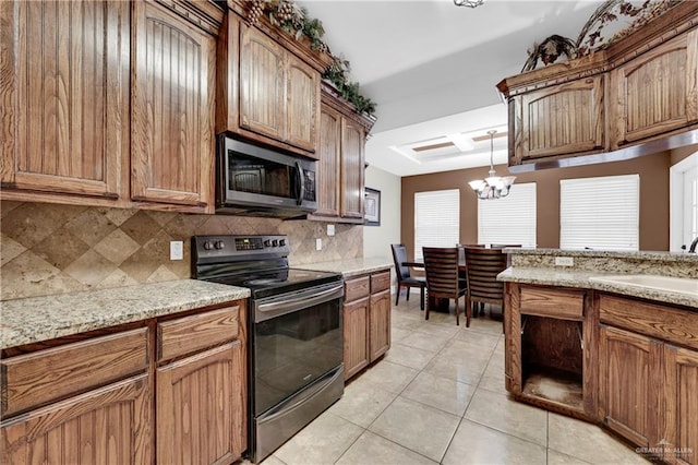 kitchen with tasteful backsplash, light tile patterned floors, electric range, an inviting chandelier, and hanging light fixtures