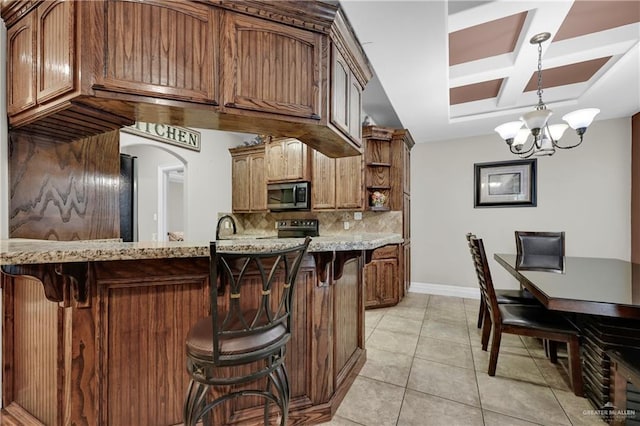 kitchen with black range with electric stovetop, hanging light fixtures, tasteful backsplash, a notable chandelier, and light tile patterned flooring