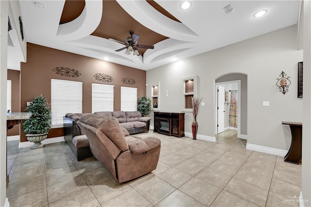 living room with light tile patterned floors, a tray ceiling, and ceiling fan