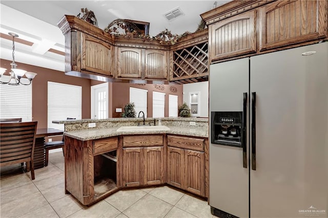 kitchen with sink, stainless steel refrigerator with ice dispenser, light tile patterned floors, a notable chandelier, and kitchen peninsula