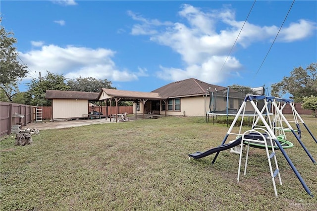 rear view of property featuring a playground, a lawn, a patio, and a trampoline