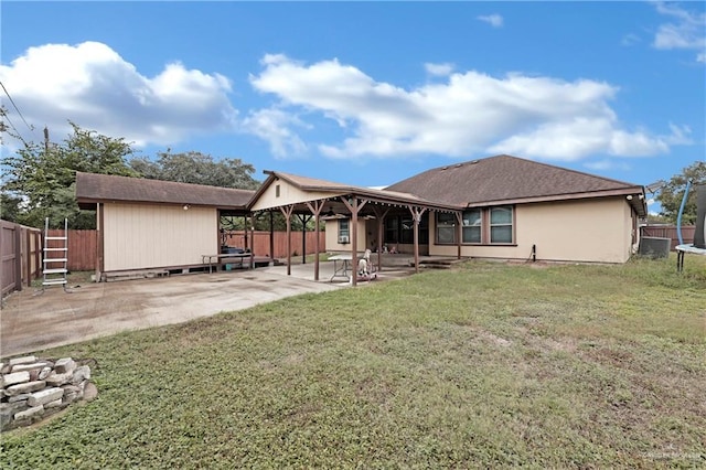 back of house with a yard, a patio, and a trampoline