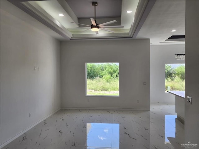 spare room with a tray ceiling and ceiling fan