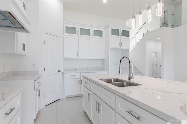 701 Helen St, Mission, TX 78574 - kitchen featuring a sink, wall chimney range hood, glass insert cabinets, hanging light fixtures, and white cabinetry