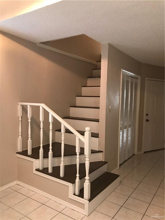 stairs with tile patterned flooring and a textured ceiling