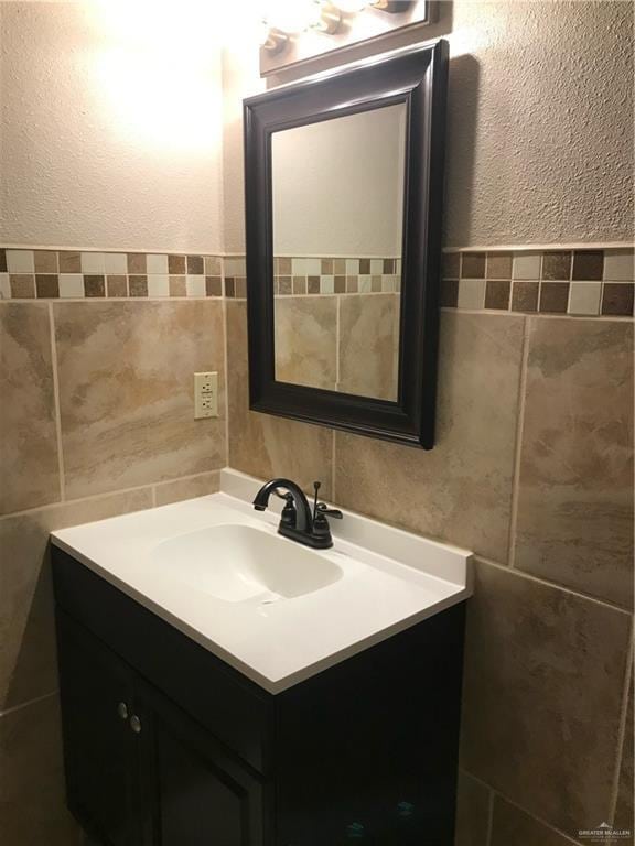 bathroom featuring vanity and tile walls