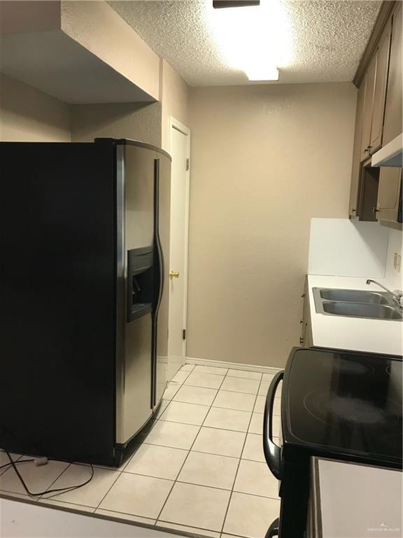 kitchen featuring sink, stainless steel fridge with ice dispenser, a textured ceiling, light tile patterned floors, and black range with electric cooktop