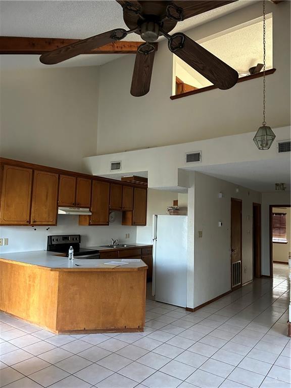 kitchen featuring white refrigerator, stainless steel electric stove, beam ceiling, and kitchen peninsula