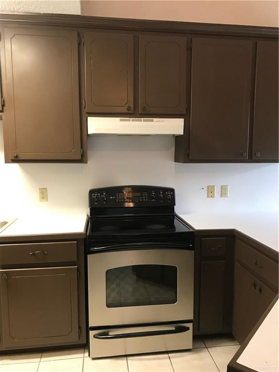 kitchen with light tile patterned flooring, dark brown cabinets, and electric stove