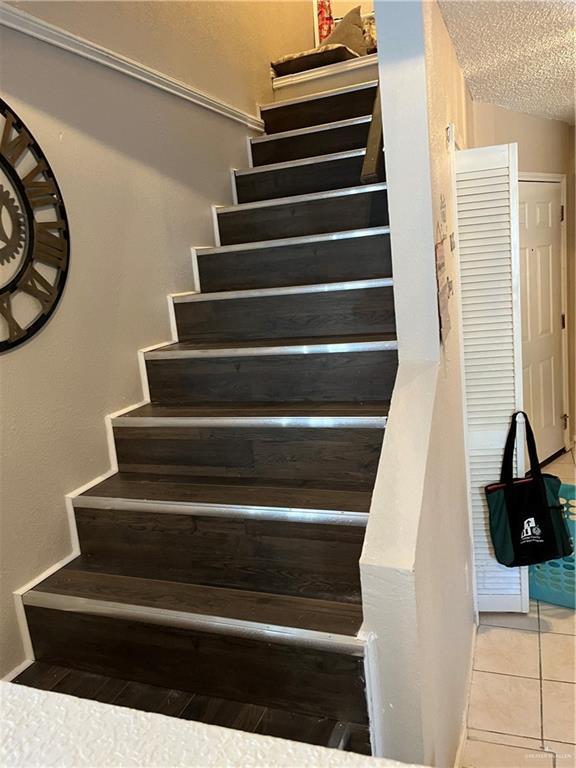 stairs featuring tile patterned flooring and a textured ceiling