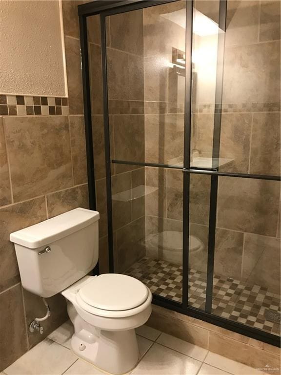 bathroom with tile patterned flooring, toilet, tile walls, and walk in shower